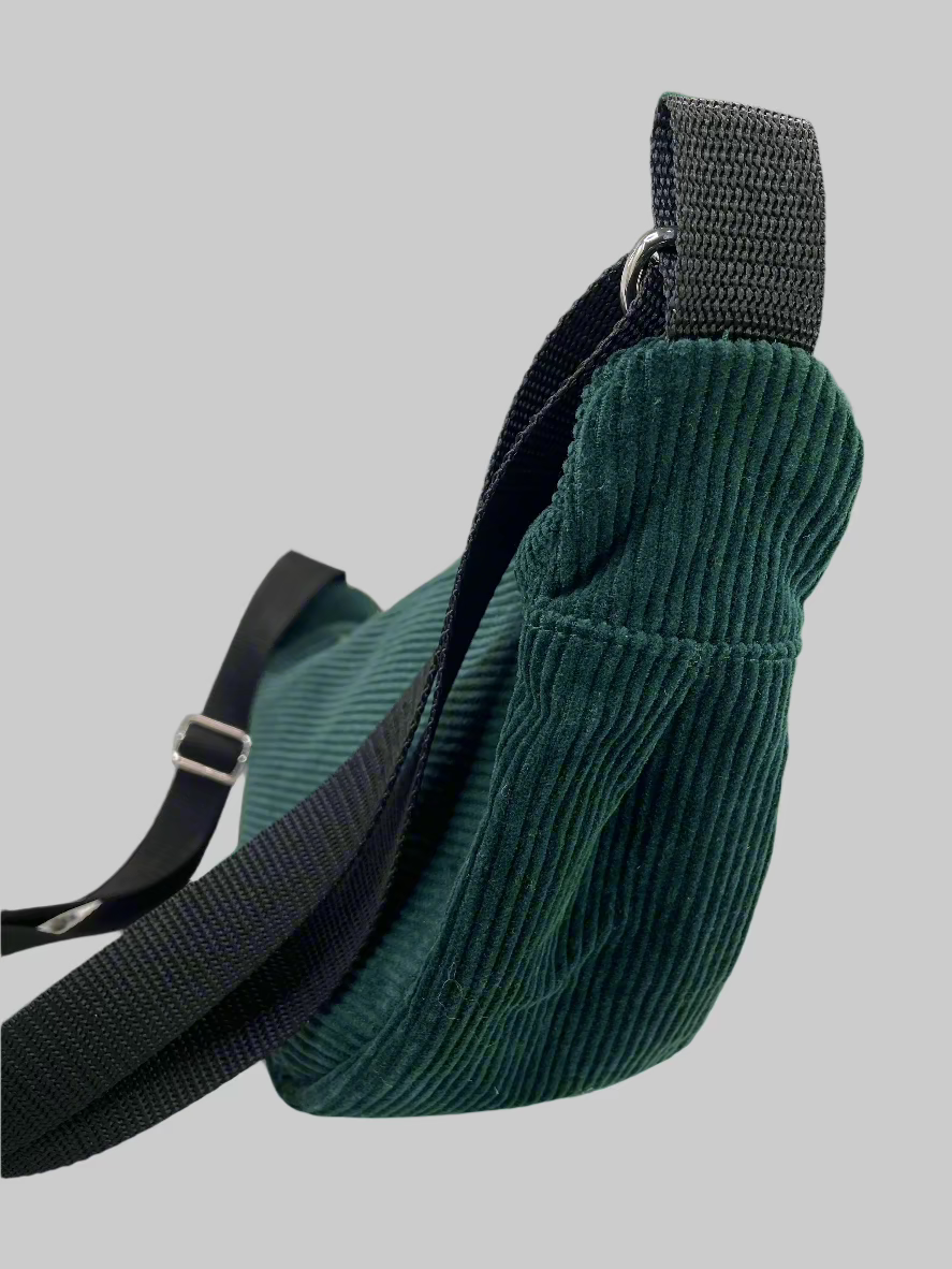 Side view of the Emerald green corduroy hobo shoulder bag, adjustable shoulder strap, zipper top, inside slip pocket.