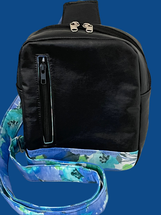 Black reclaimed vinyl from scraps of car interior. Sling bag accented with blue and green watercolor cotton fabric accent, lining and strap. Front zip pocket, back slip pocket, internal slip pocket. Front shown.